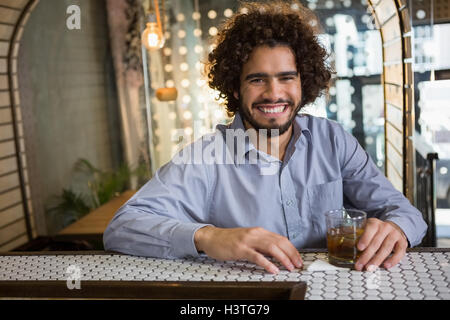 Man sitting on bar counter with glass of whisky Stock Photo