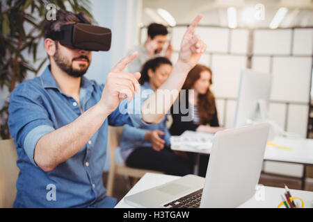Businessman gesturing while using virtual reality headset Stock Photo