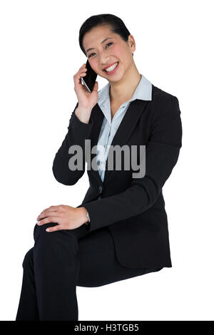 Smiling businesswoman talking on mobile phone against white background Stock Photo