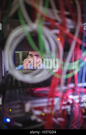 Technician talking on mobile phone while checking cables Stock Photo