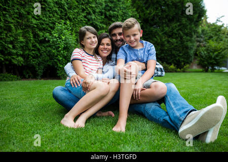 Happy family sitting on grass in park on a sunny day Stock Photo