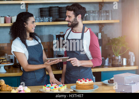 Smiling waiter and waitress using digital tablet at counter Stock Photo
