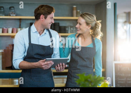 Smiling waiter and waitress interacting while using digital tablet Stock Photo
