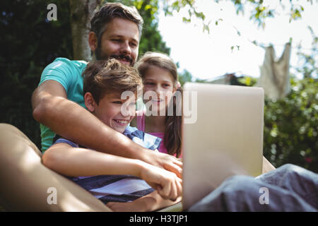 Father and kids using laptop in garden Stock Photo