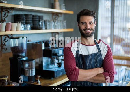 Portrait of smiling waiter standing with arms crossed Stock Photo