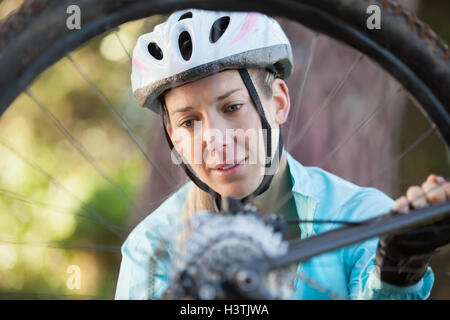 Female mountain biker examining wheel of her bicycle Stock Photo