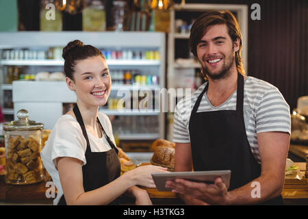 Smiling waiter and waitress using digital tablet at counter Stock Photo