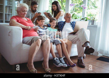 Multi-generation family using laptop, mobile phone and digital tablet Stock Photo
