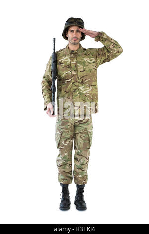 Portrait of soldier holding rifle and saluting against dark background ...