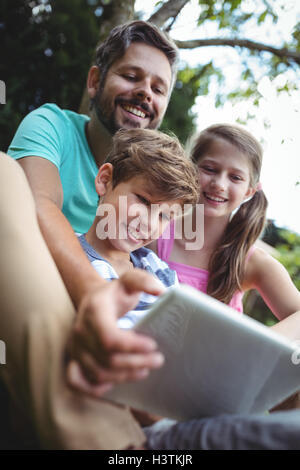 Father and kids using digital tablet in garden Stock Photo