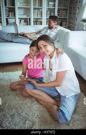 Mother and daughter sitting on floor and using digital tablet Stock Photo
