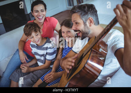Happy family sitting on sofa with a guitar Stock Photo