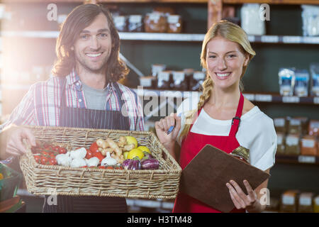 Male staff holding basket of vegetables and female staff with clipboard Stock Photo