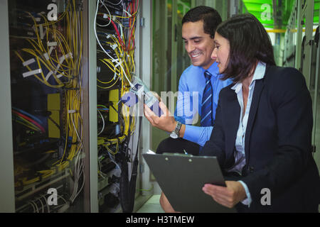 Technicians using digital cable analyzer while analyzing server Stock Photo