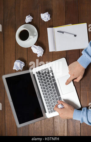 Man using laptop while writing on notepad Stock Photo
