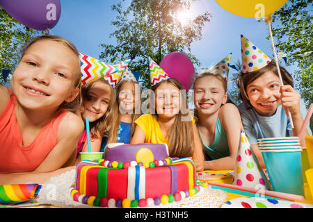 Six happy kids in party hats around birthday cake Stock Photo