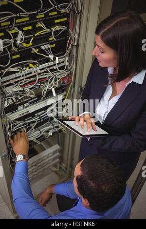 Technicians using digital tablet while analyzing server Stock Photo