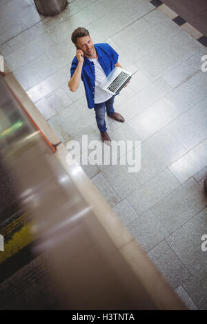 Handsome man talking on mobile phone while using laptop Stock Photo