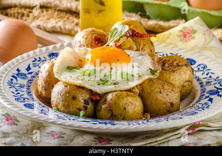 Baked potato with chili and fried egg, fresh young tomatoes and spicy chilli with herbs, great combination of flavours and spicy Stock Photo