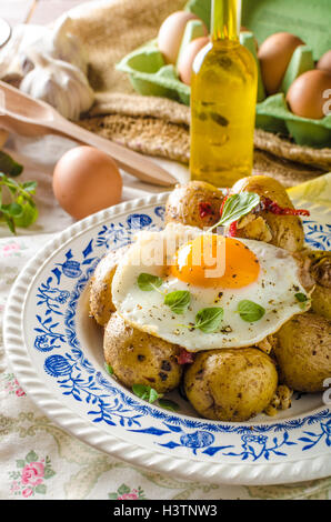 Baked potato with chili and fried egg, fresh young tomatoes and spicy chilli with herbs, great combination of flavours and spicy Stock Photo