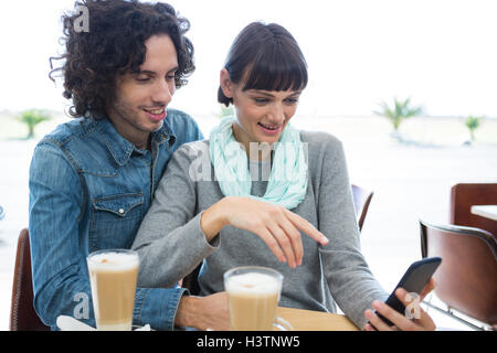 Couple sitting together and using mobile phone Stock Photo