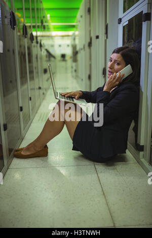 Technician talking on mobile phone while using laptop Stock Photo