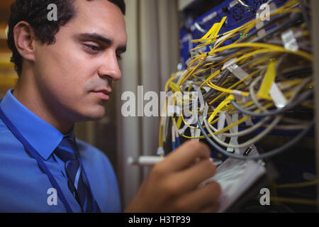 Technician maintaining record of rack mounted server on clipboard Stock Photo