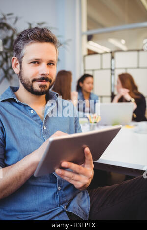 smiling businessman using digital tablet against female coworkers Stock Photo