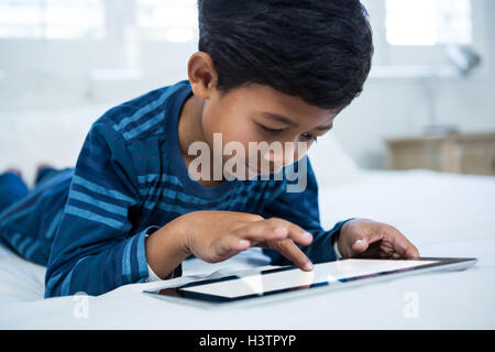 Boy using digital tablet while relaxing on bed Stock Photo
