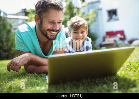Father and son using laptop in garden Stock Photo