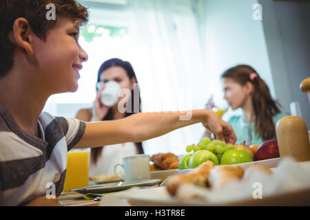 Boy picking up fruits from tray while having breakfast Stock Photo