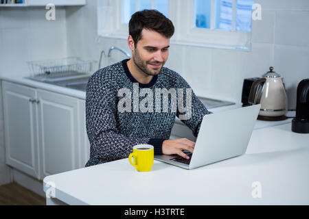 Man using laptop in the kitchen Stock Photo