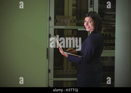 Technician using laptop while analyzing server Stock Photo