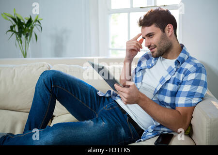 Man using digital tablet while relaxing on sofa Stock Photo
