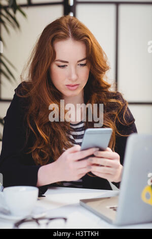 Beautiful executive using mobile phone at creative office Stock Photo
