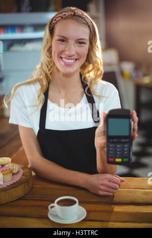 Portrait of smiling waitress holding credit card reader