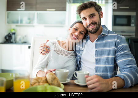 Portrait of couple sitting with arm around while having breakfast Stock Photo