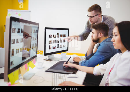 Executive using graphics tablet while colleagues discussing at creative office Stock Photo