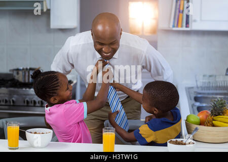 Children helping their father in tying tie Stock Photo