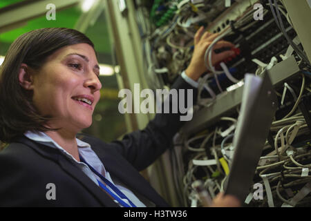Technician maintaining record of rack mounted server on clipboard Stock Photo
