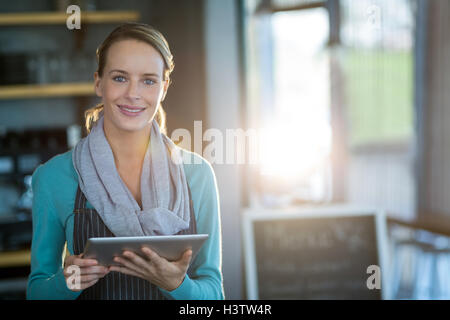 Smiling waitress using digital tablet in cafe Stock Photo