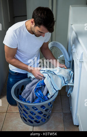 Man putting clothes into washing machine Stock Photo