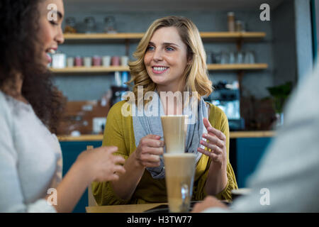 Smiling friends having a cup of cold coffee in caf├⌐ Stock Photo