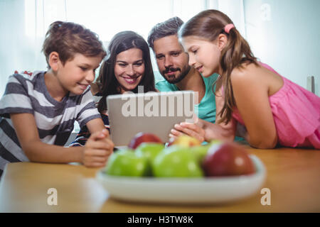 Family using digital tablet while sitting at table Stock Photo