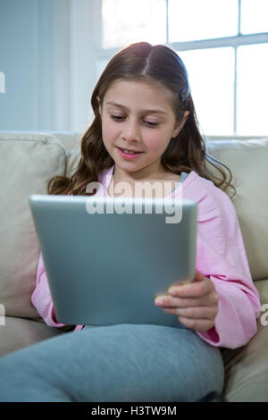 Girl using digital tablet while relaxing on sofa Stock Photo