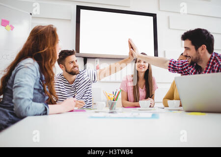 Male colleagues giving high-five in meeting at creative office Stock Photo