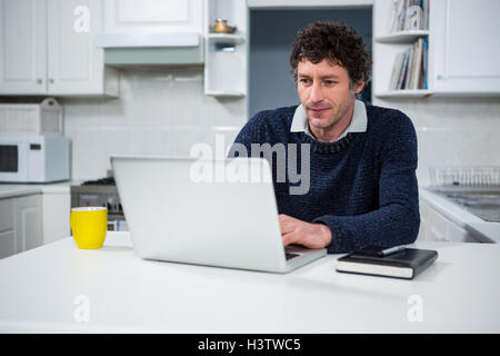 Man using laptop in the kitchen Stock Photo