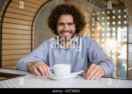 Man sitting on bar counter with cup of tea Stock Photo