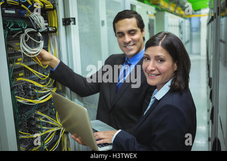Technicians using laptop while analyzing server Stock Photo