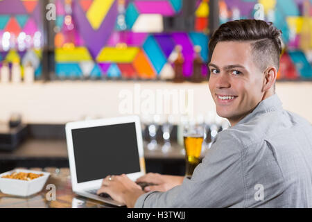 Smiling man using laptop in restaurant Stock Photo
